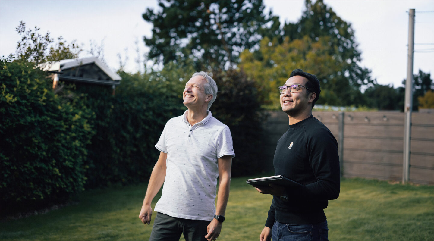Zonne-man met klant kijkt naar nieuwe zonnepanelen in de tuin